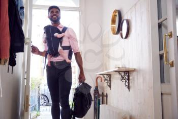 Man Carrying Baby Daughter In Sling Opens Front Door Of House