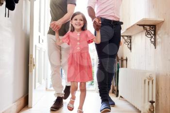 View Inside Hallway As Same Sex Male Couple With Daughter Open Front Door Of Home