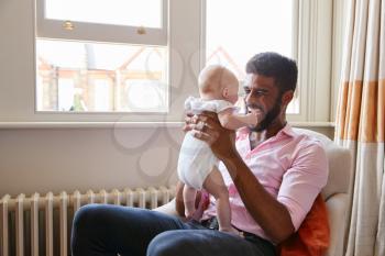 Loving Father Playing With Smiling Baby Daughter At Home