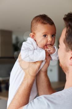 Loving Father Holding 3 Month Old Baby Daughter In Kitchen At Home