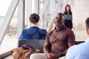 Mature Businessman Sitting And Waiting In Airport Departure Lounge