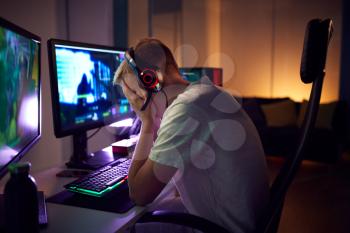 Stressed Teenage Boy Being Bullied Online Whilst Gaming At Home