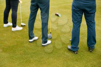 Close Up Of Legs Of Golfers Holding Clubs On Golf Tee
