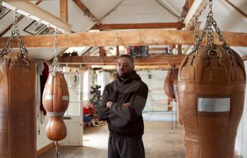 Portrait Of Male Boxer In Gym Standing By Old Fashioned Leather Punch Bag