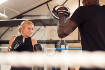 Male Personal Trainer Sparring With Female Boxer In Gym Using Training Gloves