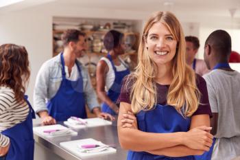 Portrait Of Smiling Woman Wearing Apron Taking Part In Cookery Class In Kitchen