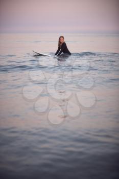 Woman Wearing Wetsuit Sitting And Floating On Surfboard On Calm  Sea