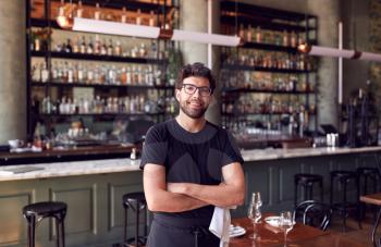 Portrait Of Male Waiter Standing In Bar Restaurant Before Service