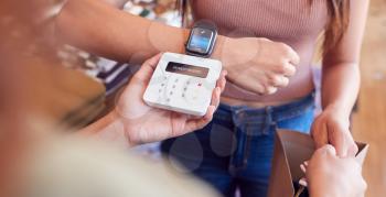 Woman In Clothing Store Making Contactless Payment With Smart Watch At Sales Desk