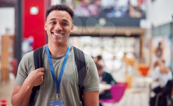 Portrait Of Smiling Male College Student In Busy Communal Campus Building