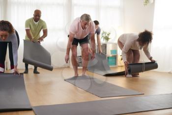 Group Of People Unrolling Exercise Mats Before Start Of Fitness Or Yoga Class In Community Center