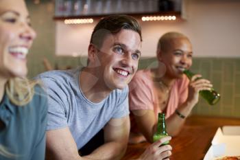 Group Of Friends Celebrating With Beers Meeting At Home And Eating Takeaway Pizza
