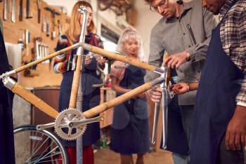 Multi-Cultural Team In Workshop Assembling Hand Built Sustainable Bamboo Bicycle Frame