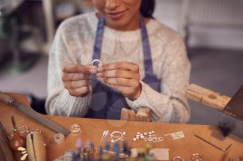 Close Up Of Female Jeweller At Bench Checking Ring She Is Working On In Studio