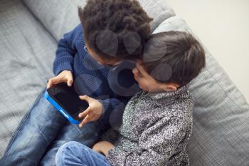 Overhead Shot Of Two Boys Gaming Together On Hand Held Devices At Home