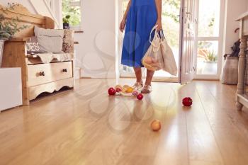 Close Up Of Woman Dropping Fresh Produce On Floor After Returning From Shopping Trip