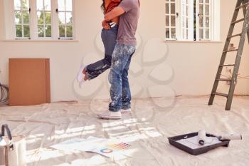 Close Up Of Couple Hugging As They Decorate Room In New Home Together