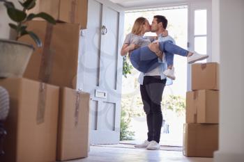 Man Carrying Woman Over Threshold Of New Home As Couple Move In Together