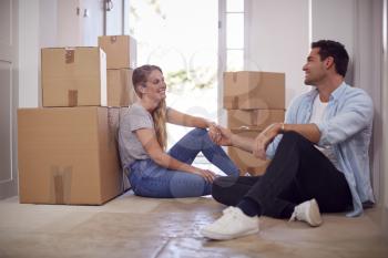 Loving Couple Taking A Break Sitting On Floor Of New Home On Moving Day