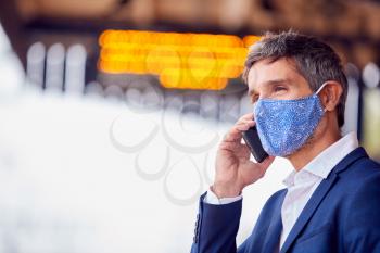 Businessman On Railway Platform Talking On Mobile Phone Wearing PPE Face Mask During Health Pandemic
