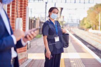Nurse In Uniform On Railway Platform Wearing PPE Face Mask Commuting To Work During Pandemic