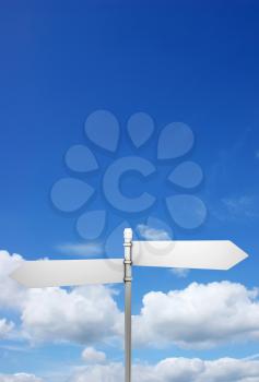 Signpost in blue sky with fluffy white clouds