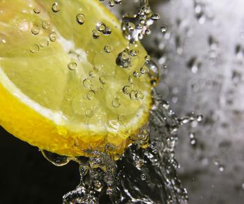 Water drops falling onto a lemon - focus is on the water drops