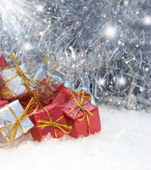 Christmas gifts in snow on a sparkly silver background