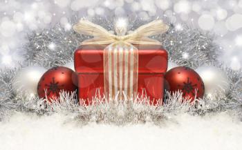 Royalty Free Clipart Image of Christmas Ornaments and a Gift on Tinsel