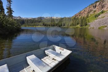 Small boat  made of white metal on a quiet mountain lake
