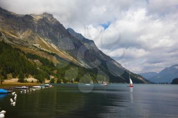 Beautiful mountain Swiss lake. Magnificent sailing yachts are reflected in smooth cold water