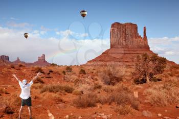 Enthusiastic tourists in Monument Valley. Famous red sandstone monoliths, fly over them colorful balloons