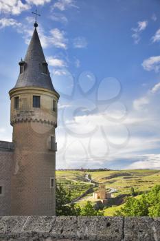Round tower of the Spanish medieval palace on a background of the rural valley shined by the sun