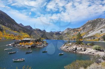 Fisherman's Paradise. Azure lake in the autumn mountains. Fishing boats circling around a small picturesque island