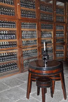 Wooden shelves with bottles of wine. Storage space for an expensive aged wines - Madeira. Round table with a bottle, which is inserted the candle