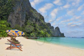 Wonderful vacation in the southern seas. Colorful beach umbrellas and sun beds for a rest on a sandy beach near the sea