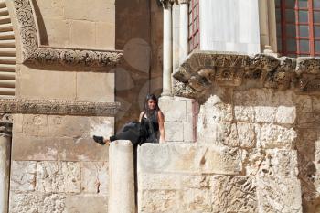 Jerusalem - March 9: Beautiful dynamic young woman dressed in black, sitting on the pillar wall of the Temple of the Holy Sepulcher March 9, 2012 in Jerusalem, Israel. The Jewish holiday of Purim