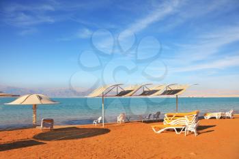 Beautiful sunny day at a beach resort. Dead Sea, the orange sand and beach chairs waiting for tourists