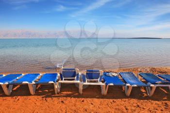 Beautiful sunny day at a beach resort. The Dead Sea, the blue beach chairs waiting for tourists