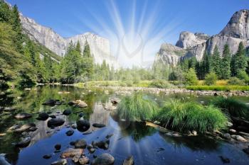 The magnificent Yosemite Valley. The huge granite monolith El Capitan and the shining sun reflected in the smooth waters of the river Mersed