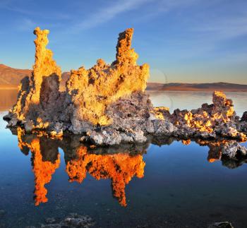 Orange sunset on Mono Lake. Outliers - bizarre limestone calcareous tufa formation reflected in the smooth water.