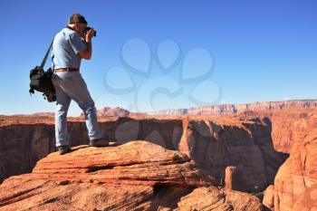 Professional photographer photographed on a steep and high bank of the river. The famous Colorado River in the picturesque Horseshoe bend. 