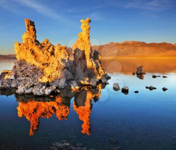  Outliers - calcareous tufa formation on the smooth water of the lake. Orange sunset. The magic of Mono Lake.