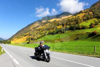 Great Highway in Austrian Alps. Among the picturesque hills at high speed motorcyclist rides