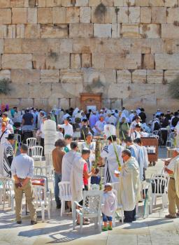 JERUSALEM, ISRAEL - SEPTEMBER 20, 2013: Morning Sukkot.  The Western Wall of the Temple in Jerusalem. Many religious Jews in traditional robes tallit gathered for prayer.