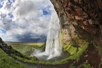   The picture was taken Fisheye lens. Summer sunny day. Large rainbow decorates a drop of water. Seljalandsfoss waterfall in Iceland.