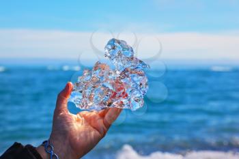 Transparent piece of ice in female hand. Iceland. The Arctic Ocean.