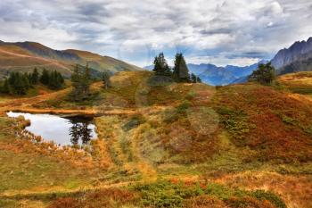  Small lake and multi-coloured autumn grasses in the Swiss Alpes