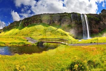 Typical landscape for the summer in Iceland. Across the stream near a waterfall Selyalandsfoss wooden bridge spanned