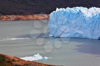 Giant lake Perito Moreno glacier. White-blue ice massif multimeter height rises over the lake Argentino